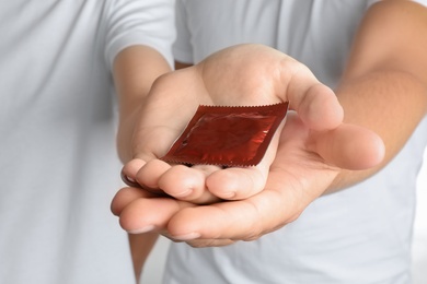 Photo of Young gay couple holding condom together, closeup