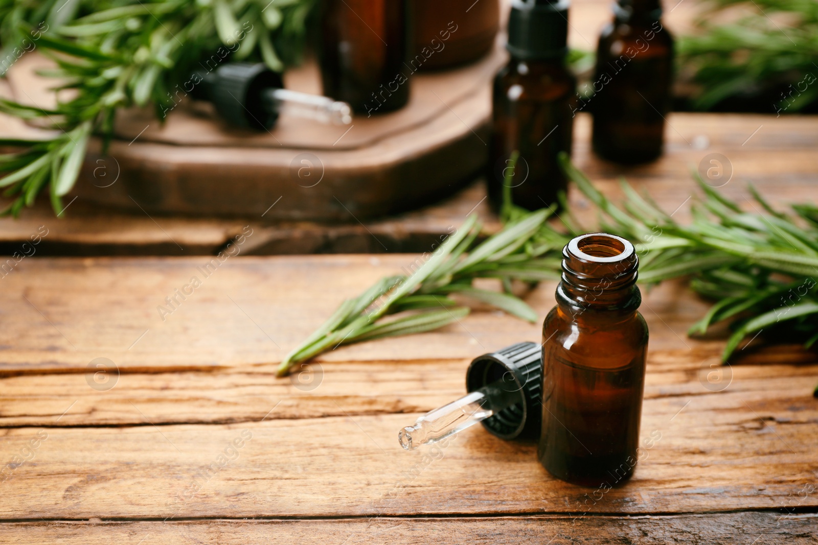 Photo of Bottle of rosemary essential oil on wooden table. Space for text