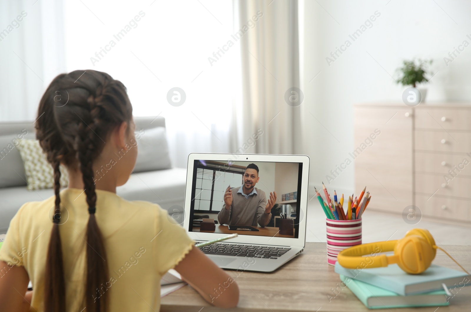 Photo of Distance learning, studying at home. Girl having online school lesson with teacher during quarantine and lockdown due to Covid-19 pandemic