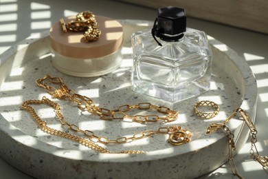 Photo of Metal chains, perfume and cream on table. Luxury jewelry