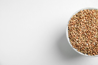 Bowl with green buckwheat on white table, top view. Space for text