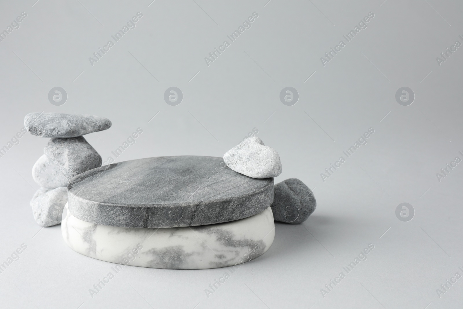 Photo of Presentation for product. Stone podium and pebbles on light grey background. Space for text