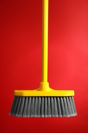 Plastic broom on red background. Cleaning tool