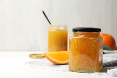 Photo of Delicious orange marmalade in jar on white table, space for text
