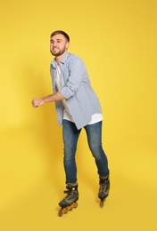 Photo of Young man with inline roller skates on color background