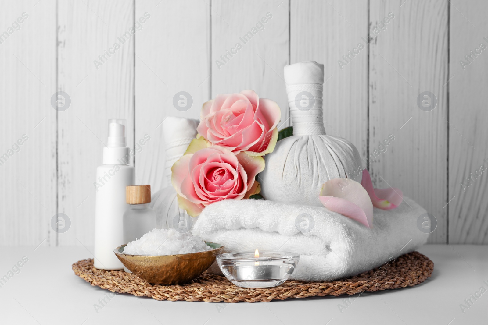 Photo of Composition with different spa products, candle and roses on white table against wooden background