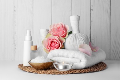 Photo of Composition with different spa products, candle and roses on white table against wooden background