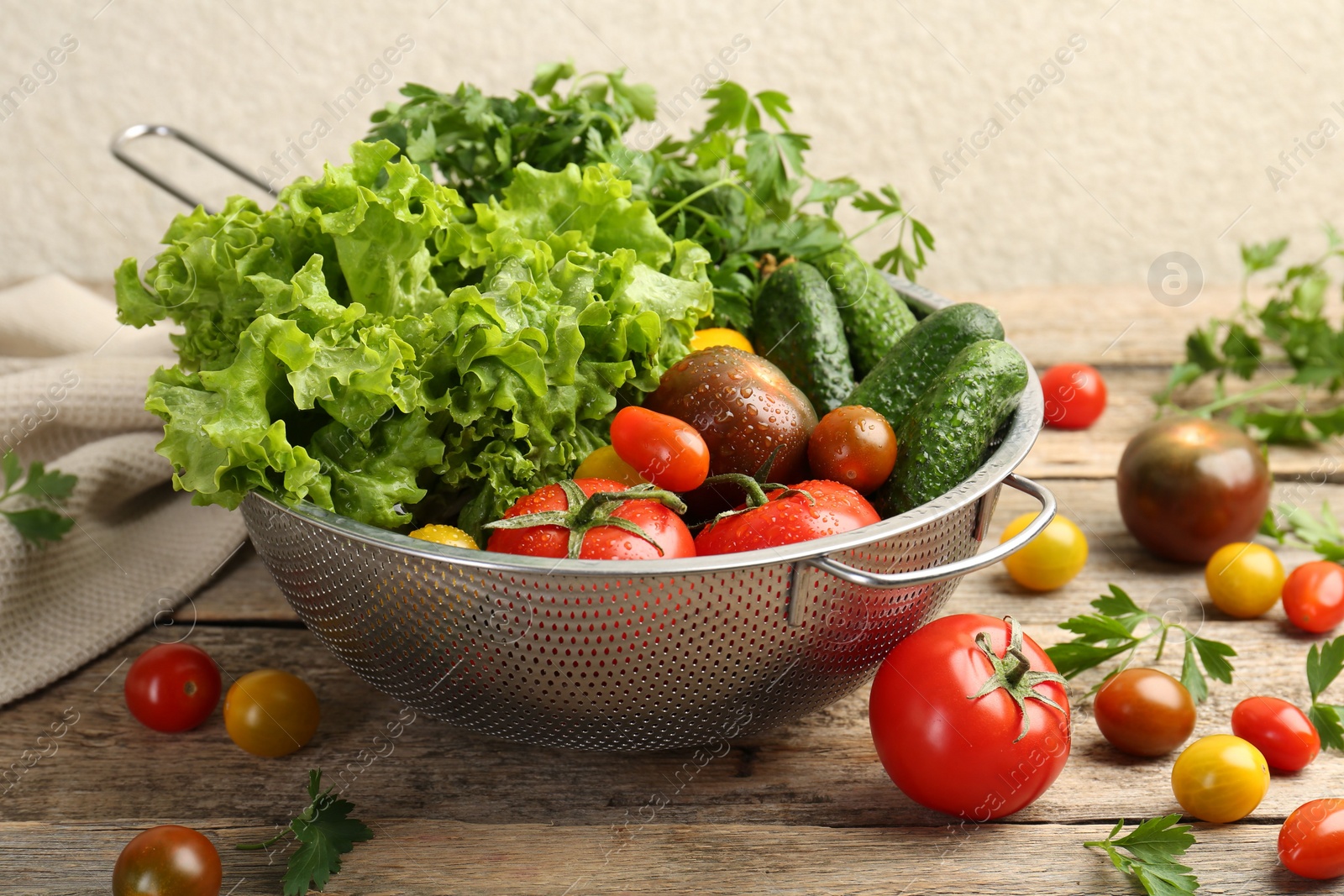 Photo of Wet vegetables in colander on wooden table, closeup