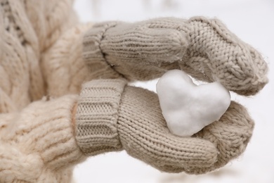 Photo of Woman holding heart made of snow, closeup view