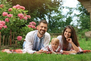 Happy family in Ukrainian national clothes on green grass outdoors