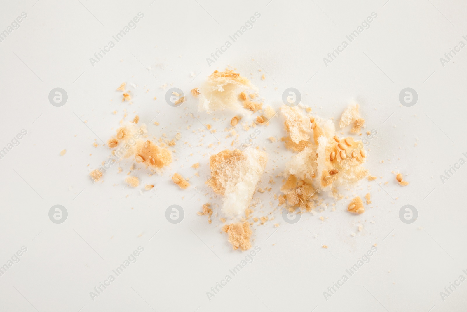 Photo of Scattered bread crumbs on white background, top view