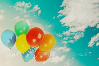 Image of Colorful balloons flying in blue sky with clouds. Space for text