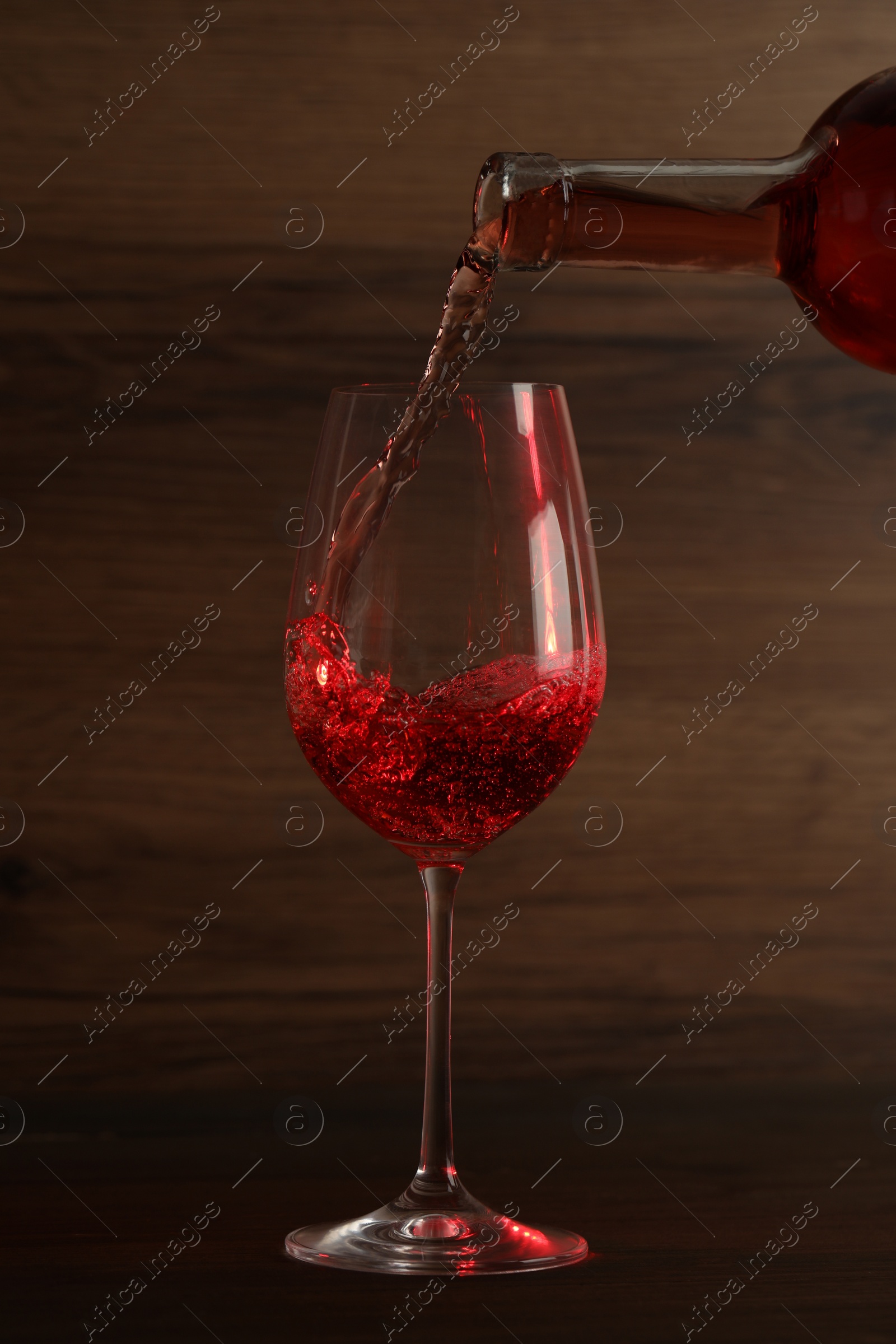 Photo of Pouring wine into glass on wooden background