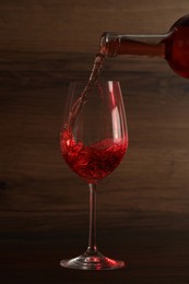 Pouring wine into glass on wooden background