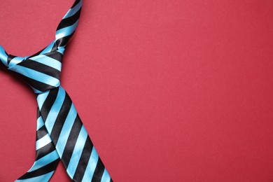 Photo of Stylish striped necktie on red background, top view. Space for text