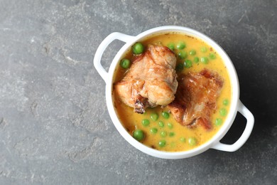 Photo of Tasty cooked rabbit meat with sauce and peas on grey table, top view. Space for text