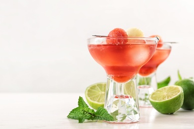 Photo of Glass of melon and watermelon ball cocktail on white wooden table. Space for text