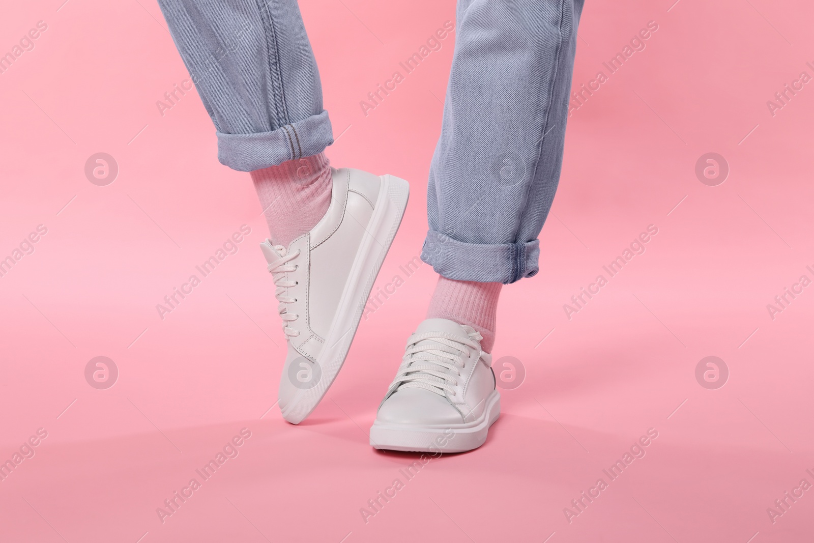 Photo of Woman wearing stylish white sneakers on pink background, closeup