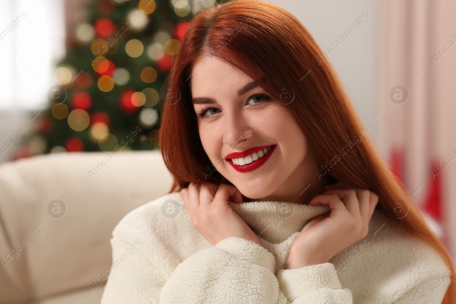 Photo of Beautiful young woman on sofa tree at home, space for text. Celebrating Christmas