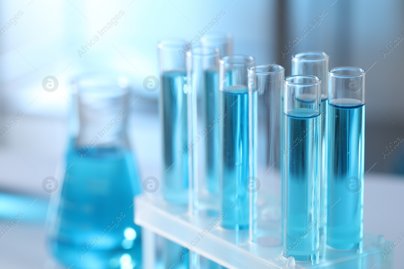 Photo of Test tubes with light blue liquid in laboratory, closeup. Space for text