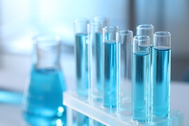 Test tubes with light blue liquid in laboratory, closeup. Space for text