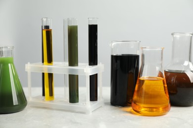 Photo of Laboratory glassware with different types of oil on white table
