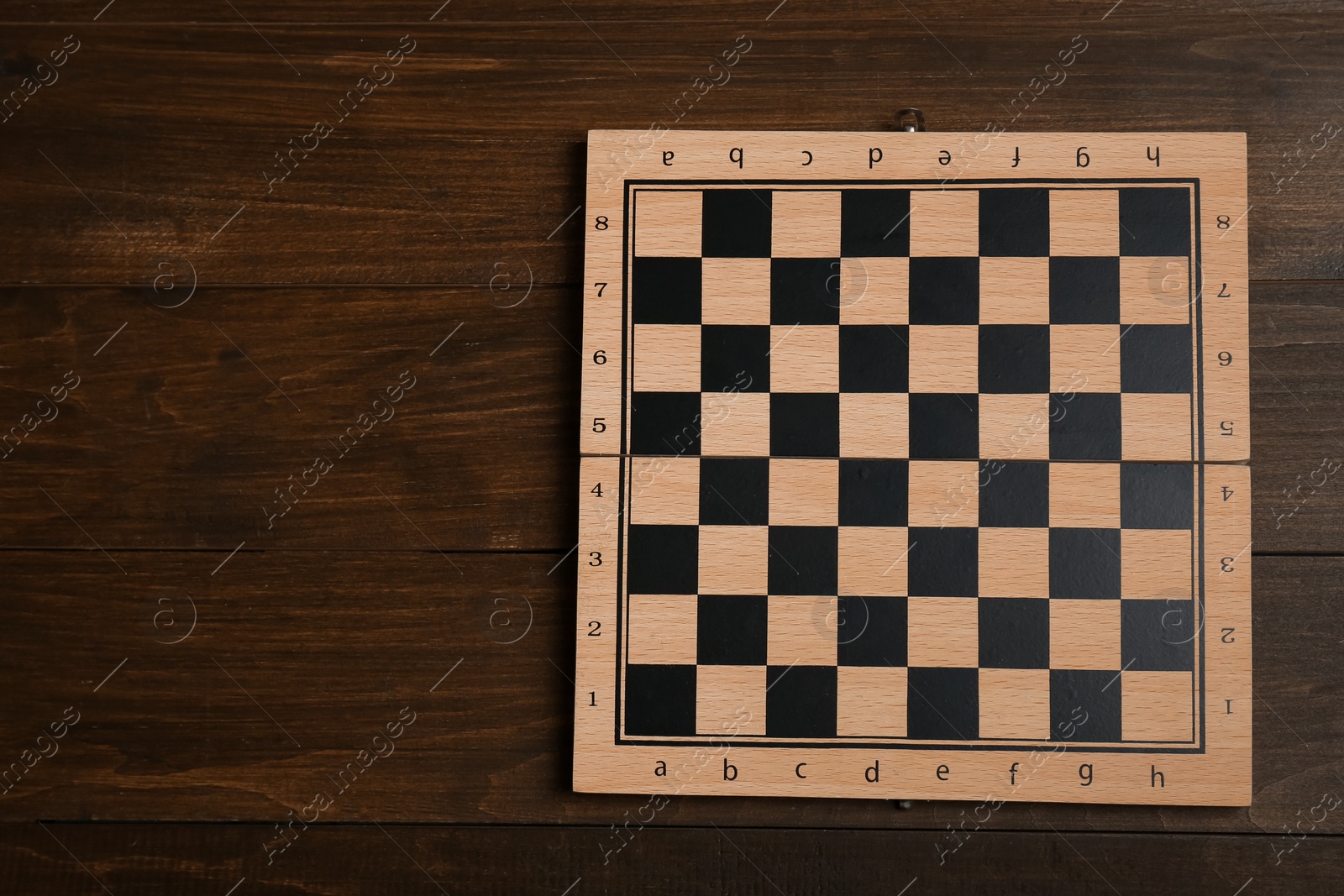 Photo of Game checkerboard on wooden table, top view. Space for text