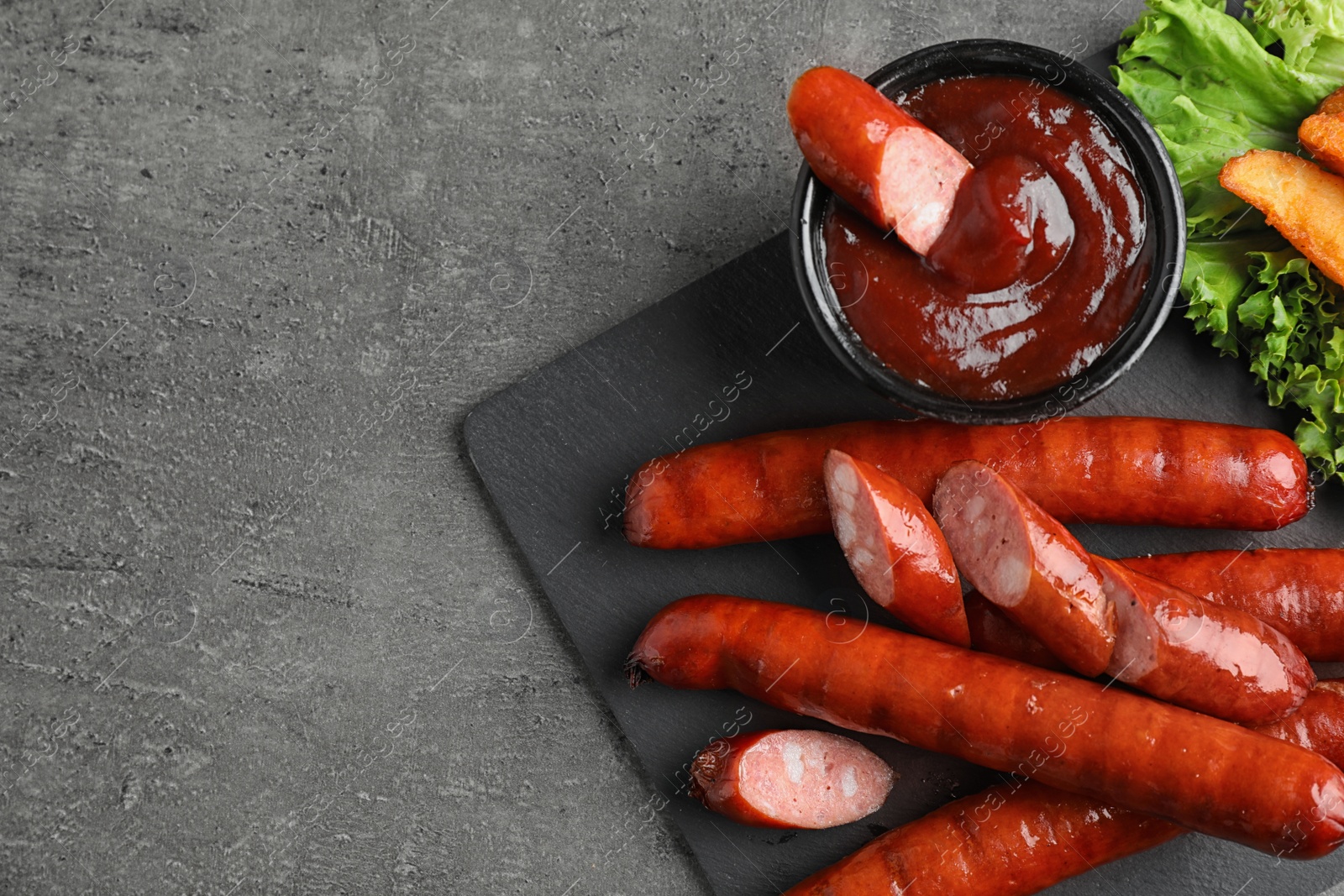 Photo of Delicious grilled sausages and vegetables on grey table, flat lay. Space for text