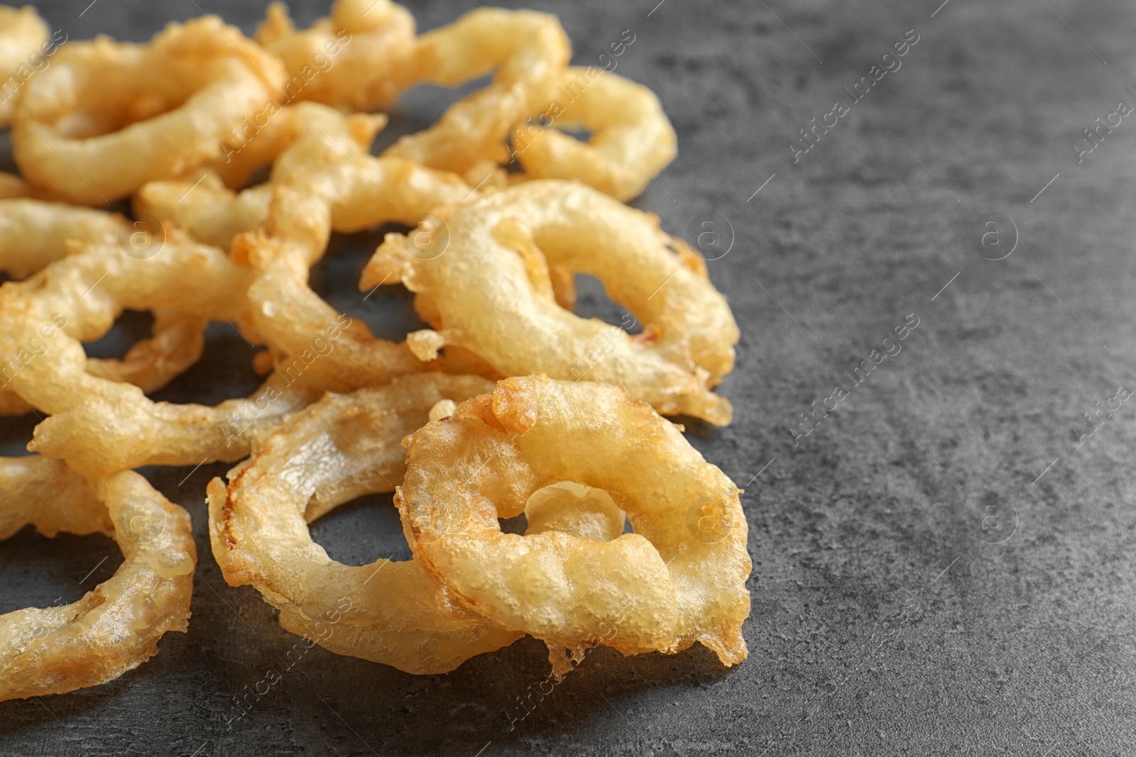 Photo of Delicious golden breaded and deep fried crispy onion rings on gray background, closeup