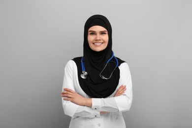 Muslim woman wearing hijab, medical uniform with stethoscope on light gray background