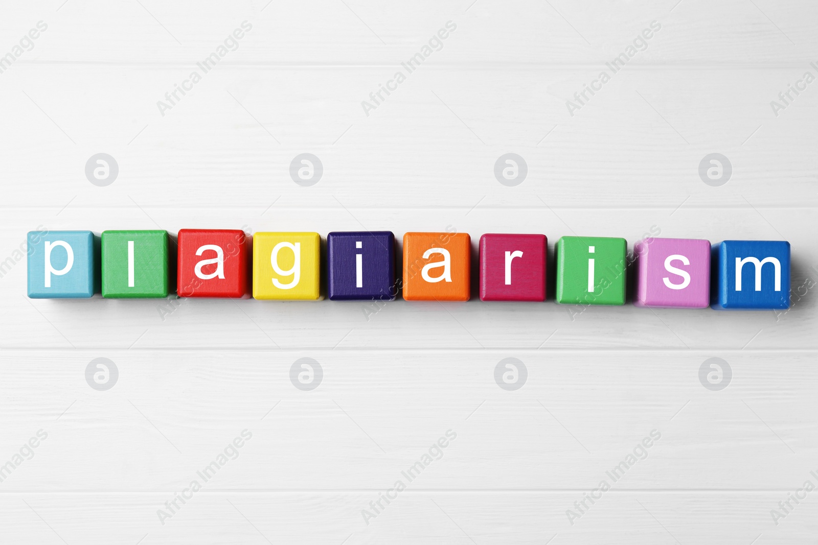 Photo of Colorful cubes with word Plagiarism on white wooden table, flat lay