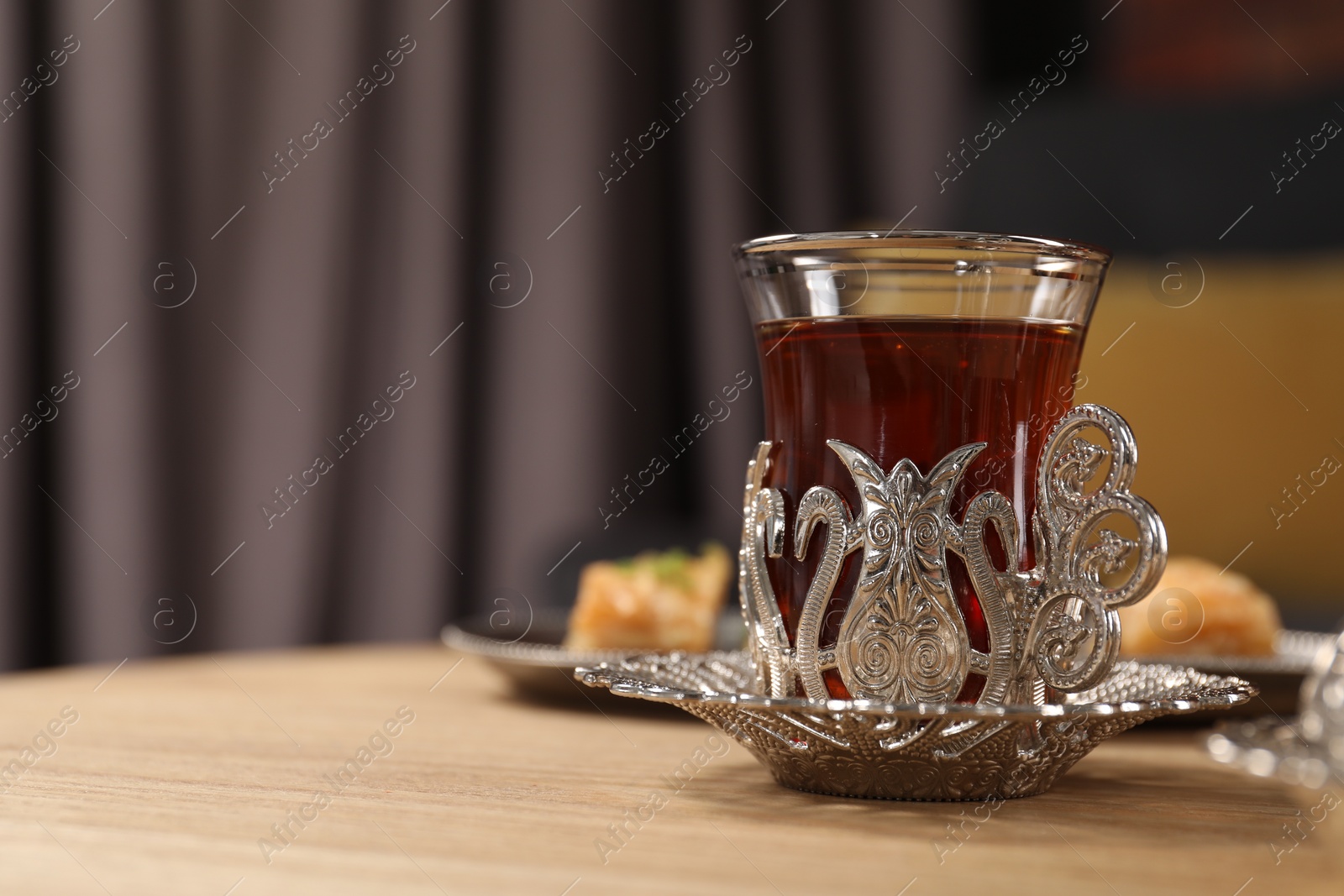 Photo of Glass of traditional Turkish tea in vintage holder on wooden table. Space for text