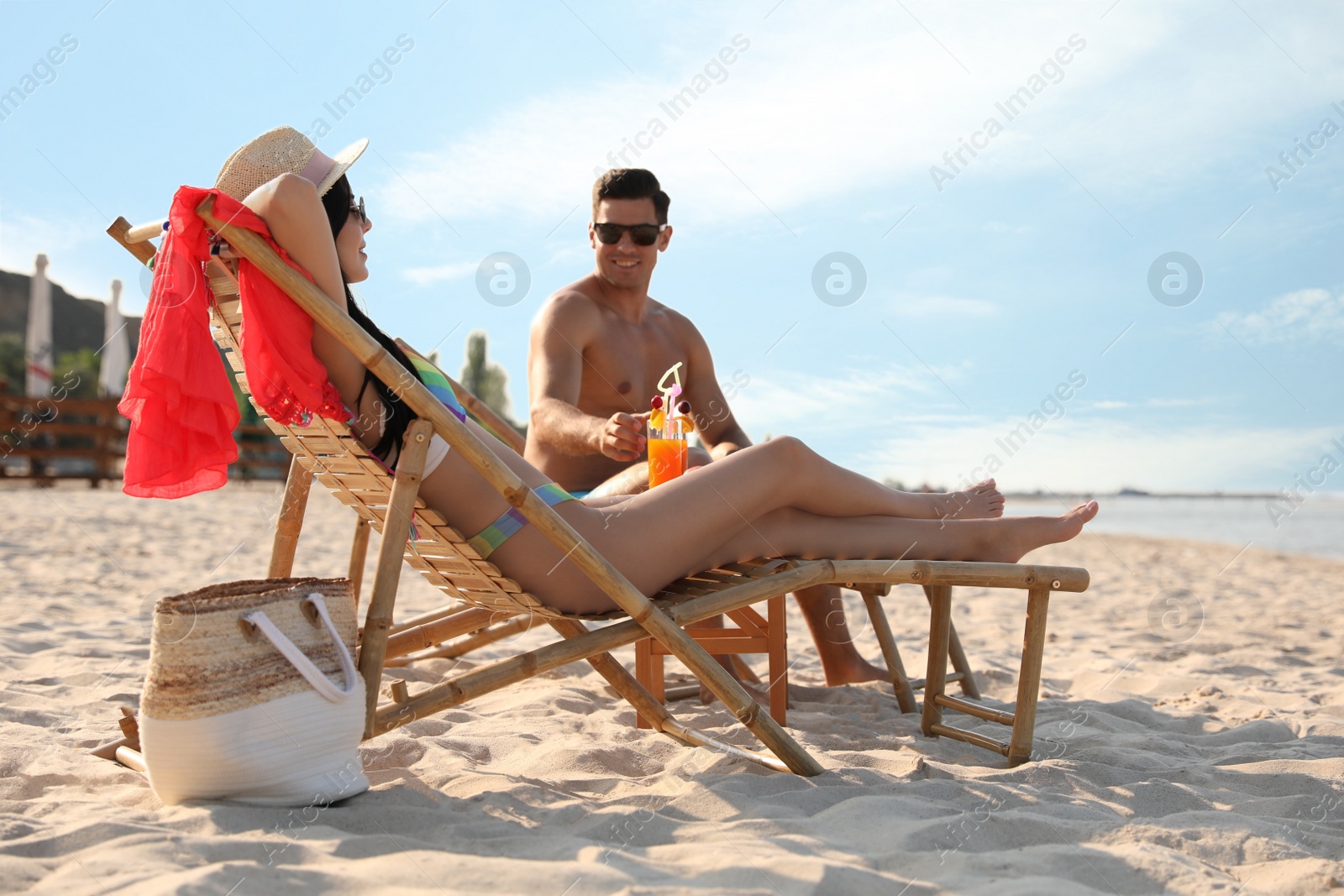Photo of Couple resting on sunny beach at resort