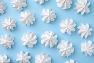 Tasty meringue cookies on light blue background, flat lay