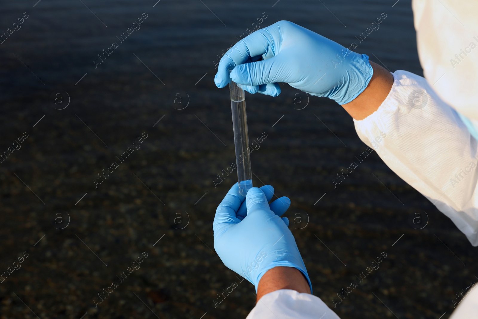 Photo of Scientist with test tube taking sample from river for analysis, closeup