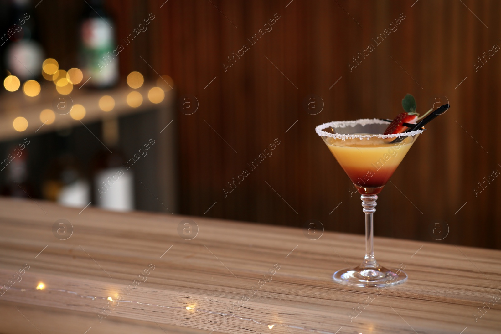 Photo of Delicious strawberry martini cocktail on table in bar, space for text