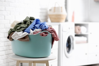 Plastic basket with dirty laundry indoors, space for text