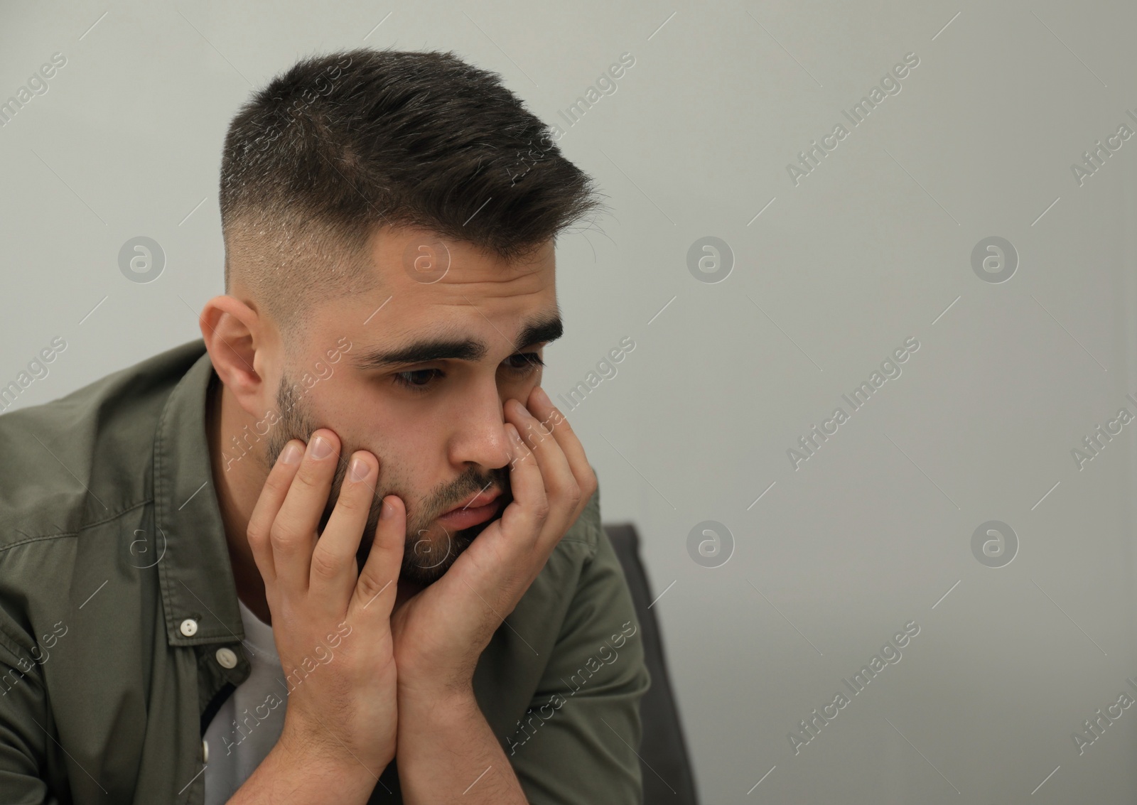 Photo of Portrait of sad man near light grey wall. Space for text