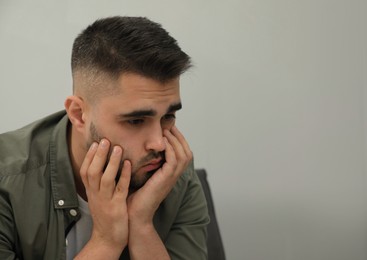 Photo of Portrait of sad man near light grey wall. Space for text