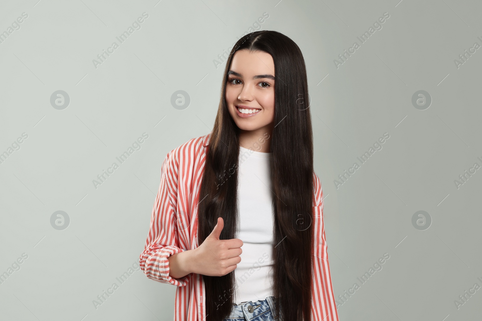 Photo of Teenage girl showing thumb up on light grey background