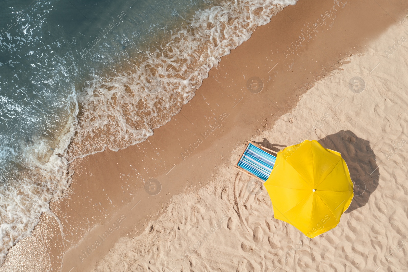 Yellow beach umbrella and sunbed on sandy coast near sea, aerial view. Space for text Image of Yellow beach umbrella and sunbed on sandy coast near sea, aerial view. Space for text