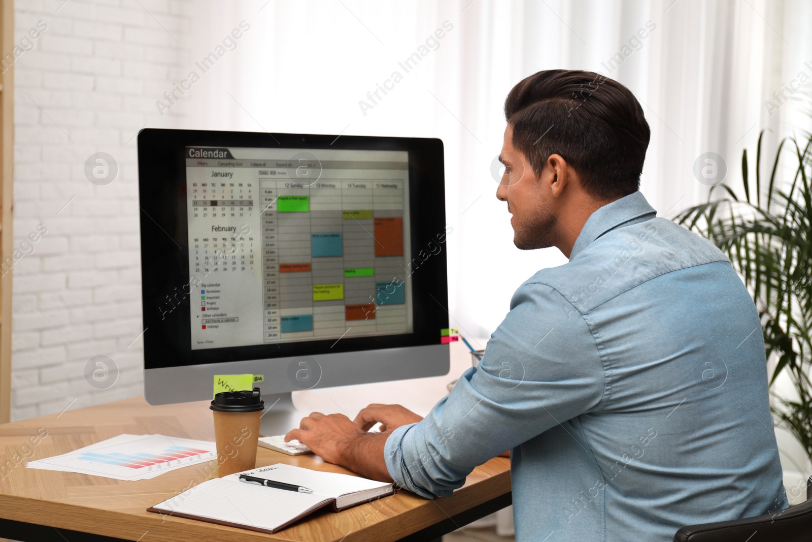 Photo of Handsome man using calendar app on computer in office