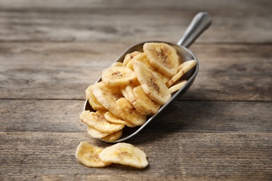Photo of Scoop with banana slices on wooden background. Dried fruit as healthy snack
