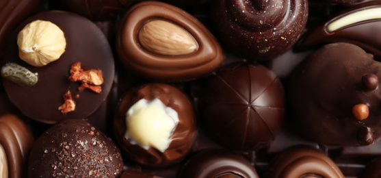 Image of Many different tasty chocolate candies as background, banner design 