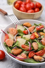 Delicious pomelo salad with tomatoes and mussels on white textured table, closeup