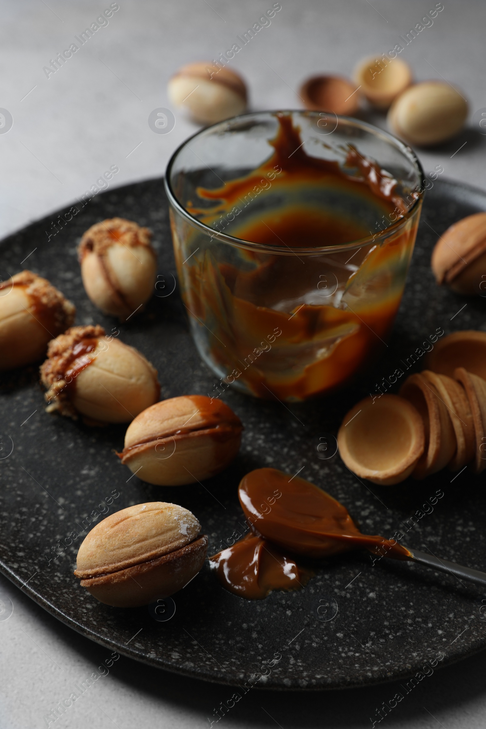 Photo of Delicious walnut shaped cookies with condensed milk on grey table, closeup