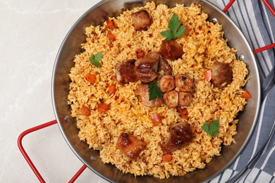 Frying pan with delicious rice pilaf on light background, top view