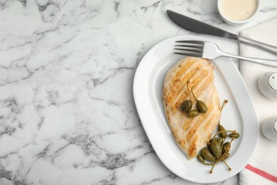 Delicious cooked chicken fillet with capers served on white marble table, flat lay. Space for text