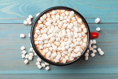 Photo of Tasty hot chocolate with marshmallows on light blue wooden table, top view