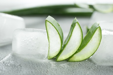 Slices of aloe vera and ice cubes on gray table